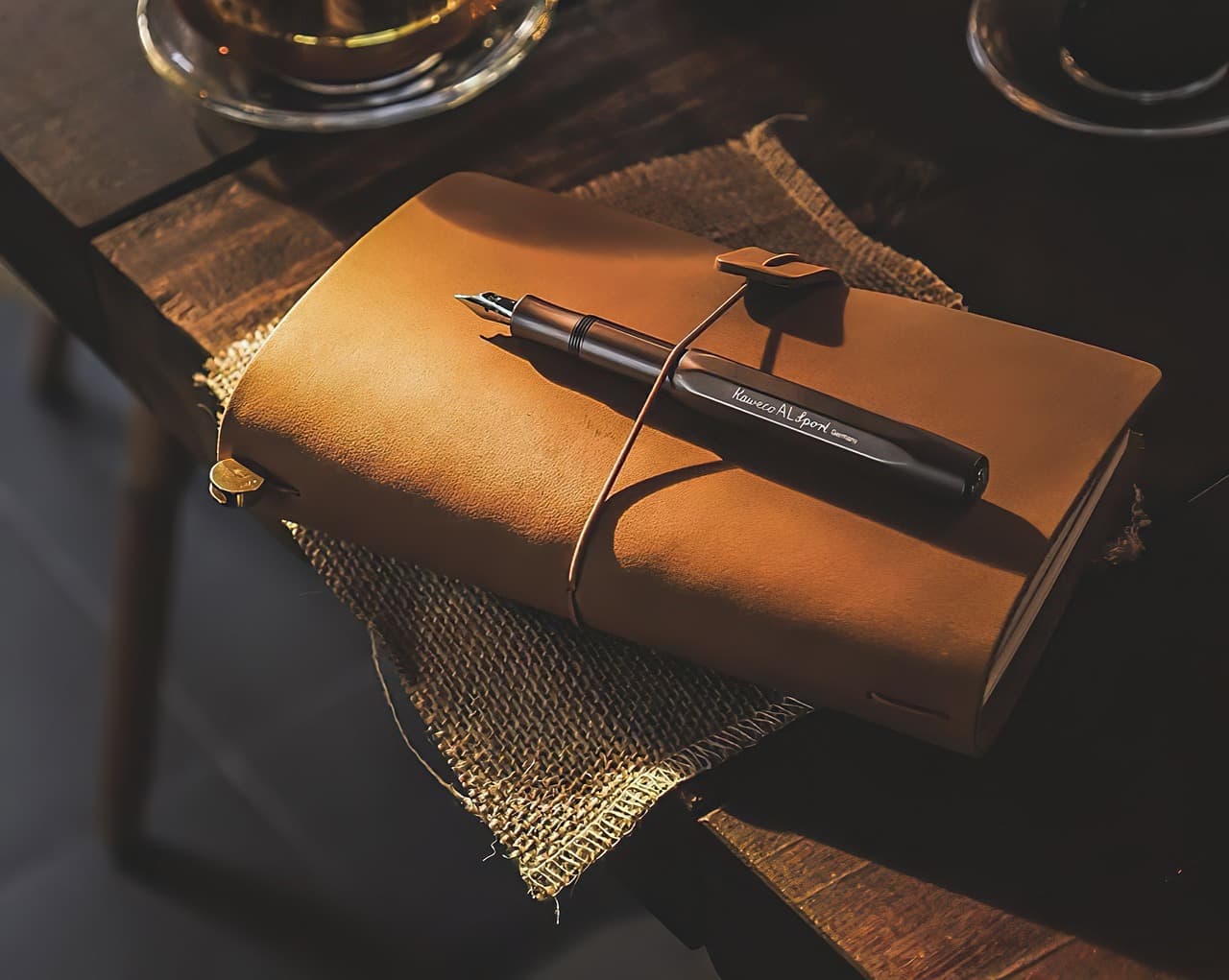 A leather-bound notebook with a pen in warm light.