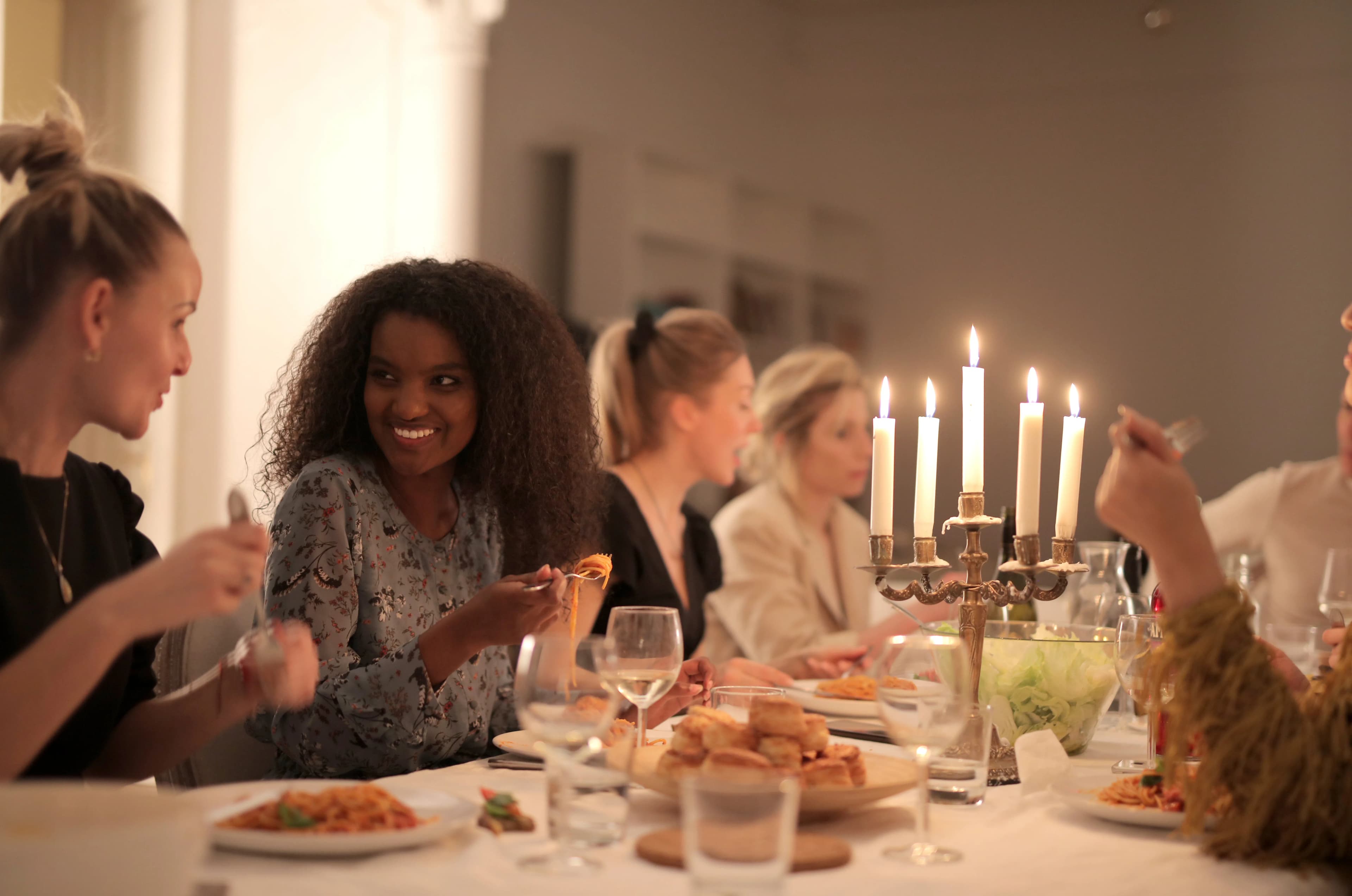 Friends laughing together at a candlelit dinner table.
